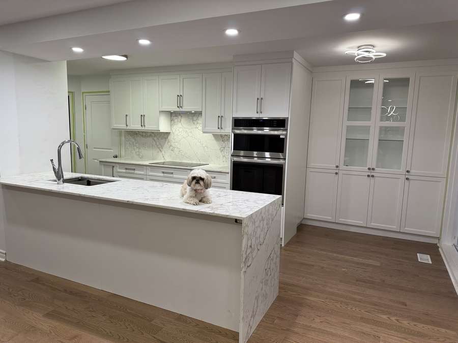 White shaker kitchen with waterfall quartz island and a small dog, by Limakdéco