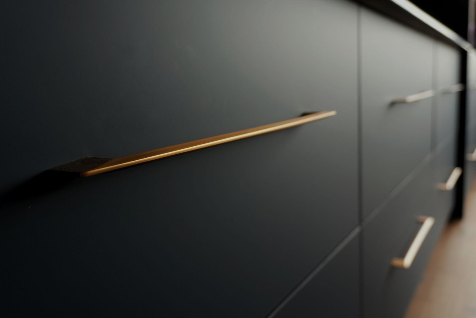 Brass bar pulls on matte charcoal drawer fronts