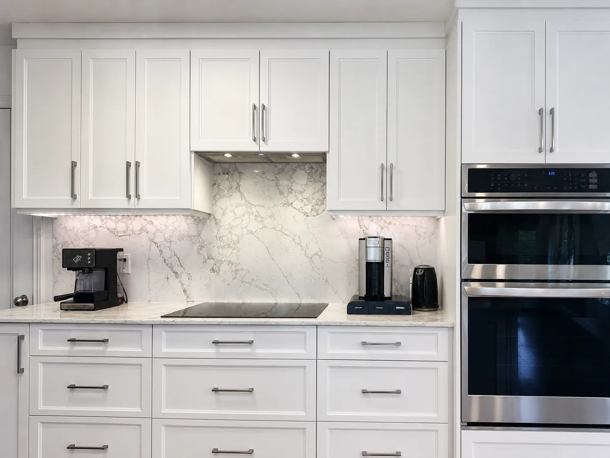 White shaker kitchen with full height Renoir quartz backsplash in Bois-Franc, by Limakdéco